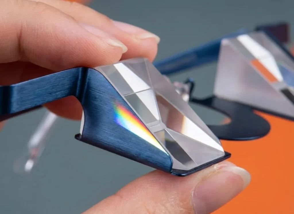 Close-up macro shot of high-quality BK7 glass prism belay glasses held in hand, showing optical clarity and light refraction.