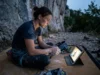 How to Watch Climbing Competitions: The 2026 Stream Matrix A climber covered in chalk watches a live stream of a climbing world cup on a tablet while resting at the base of a cliff.