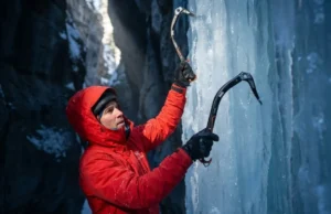 Why Cold Ice Shatters: Brittle Fracture Mechanics Guide A professional ice climber in Arc'teryx gear scaling a brittle blue ice pillar in a frozen canyon, illuminated by a shaft of cold sunlight highlighting the texture of the frozen waterfall.