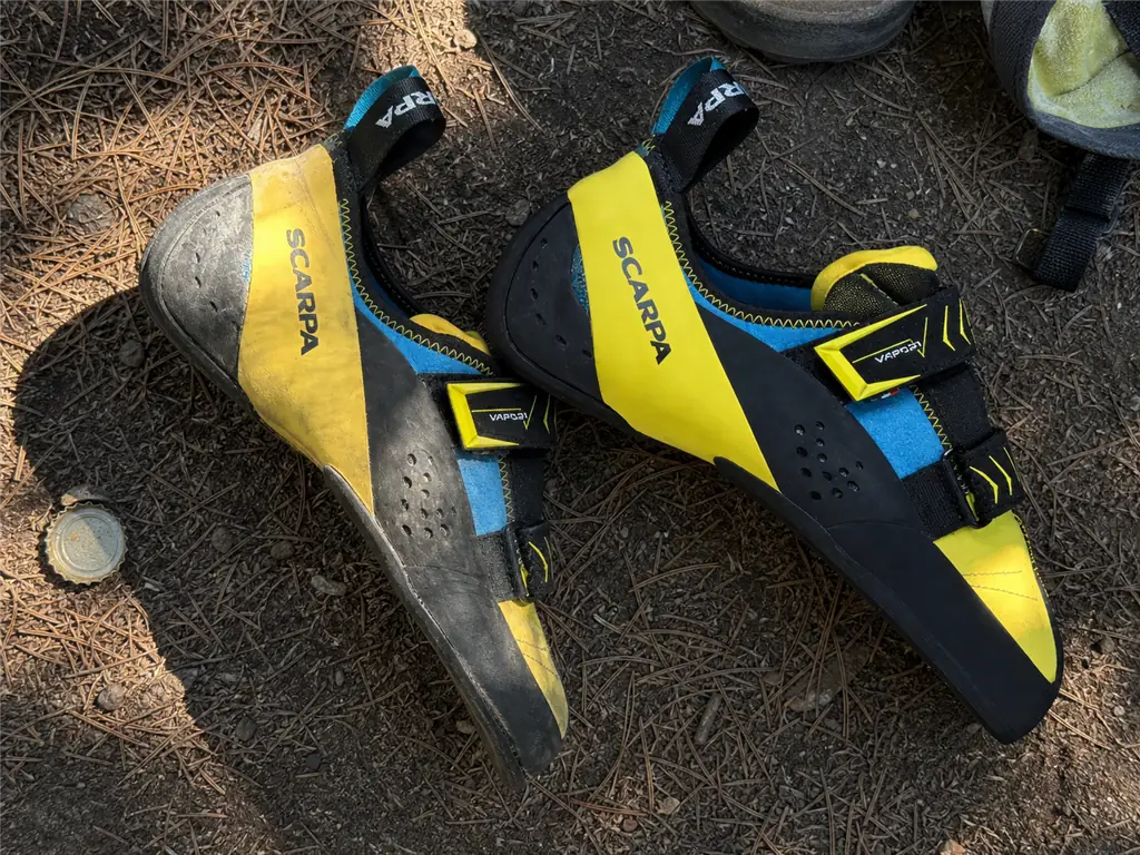 A relaxed, flattening downturned climbing shoe beside a newer pair showing how downturn fades over time