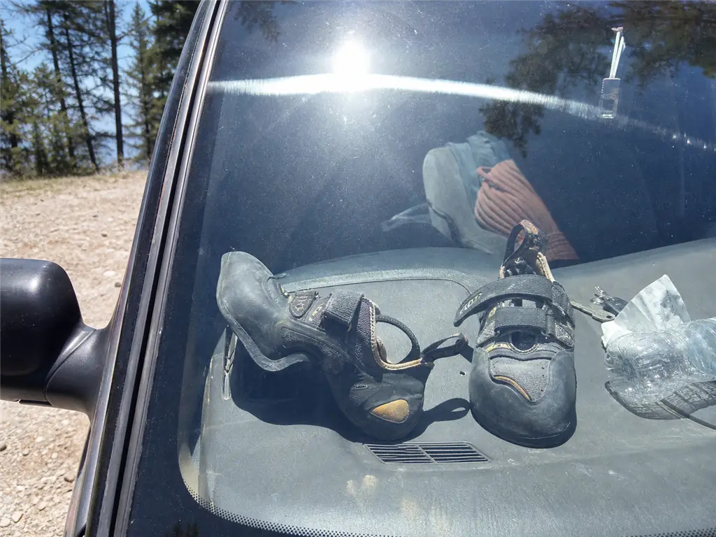 Climbing shoes left baking on a sunlit car dashboard, the heat exposure that destroys climbing shoe downturn