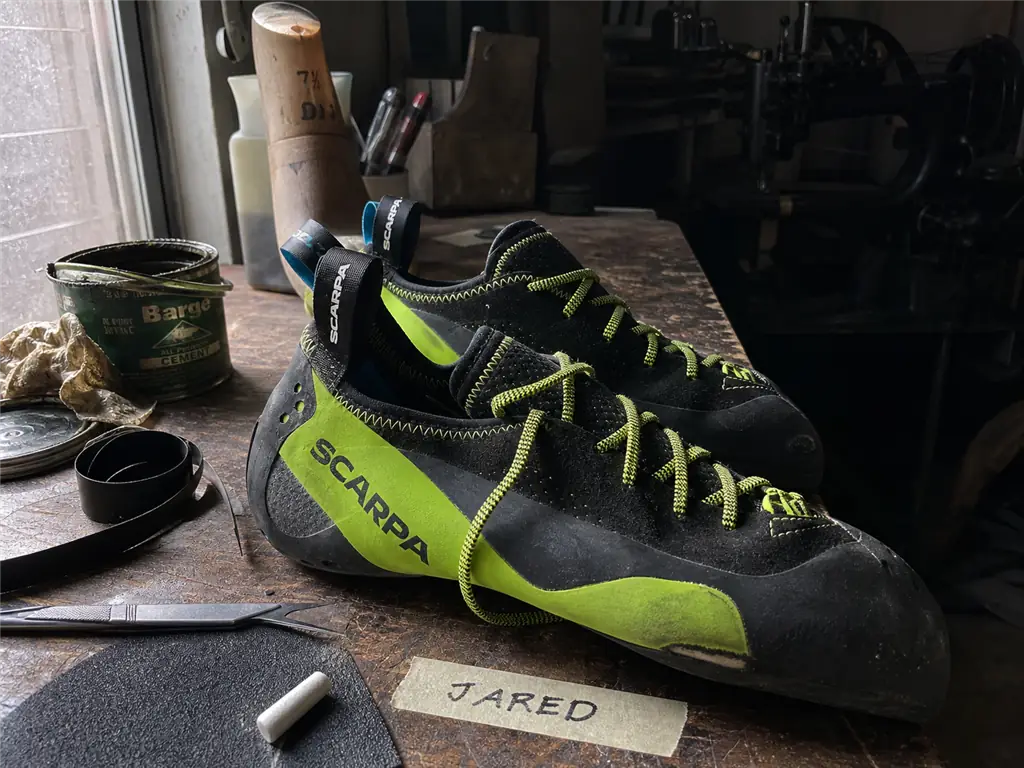 Worn climbing shoes on a resoler's bench, where a resole and rand repair restore climbing shoe downturn