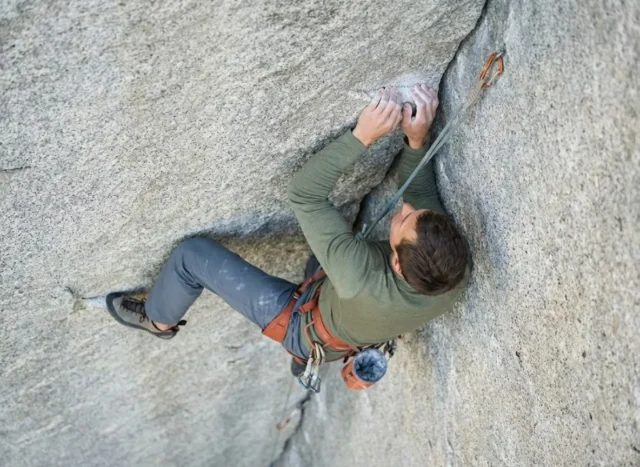 alpine-draws-rope-drag-guide Climber on a granite corner route using an alpine draw to straighten the rope path, wearing Arc'teryx gear and using a Mammut rope.