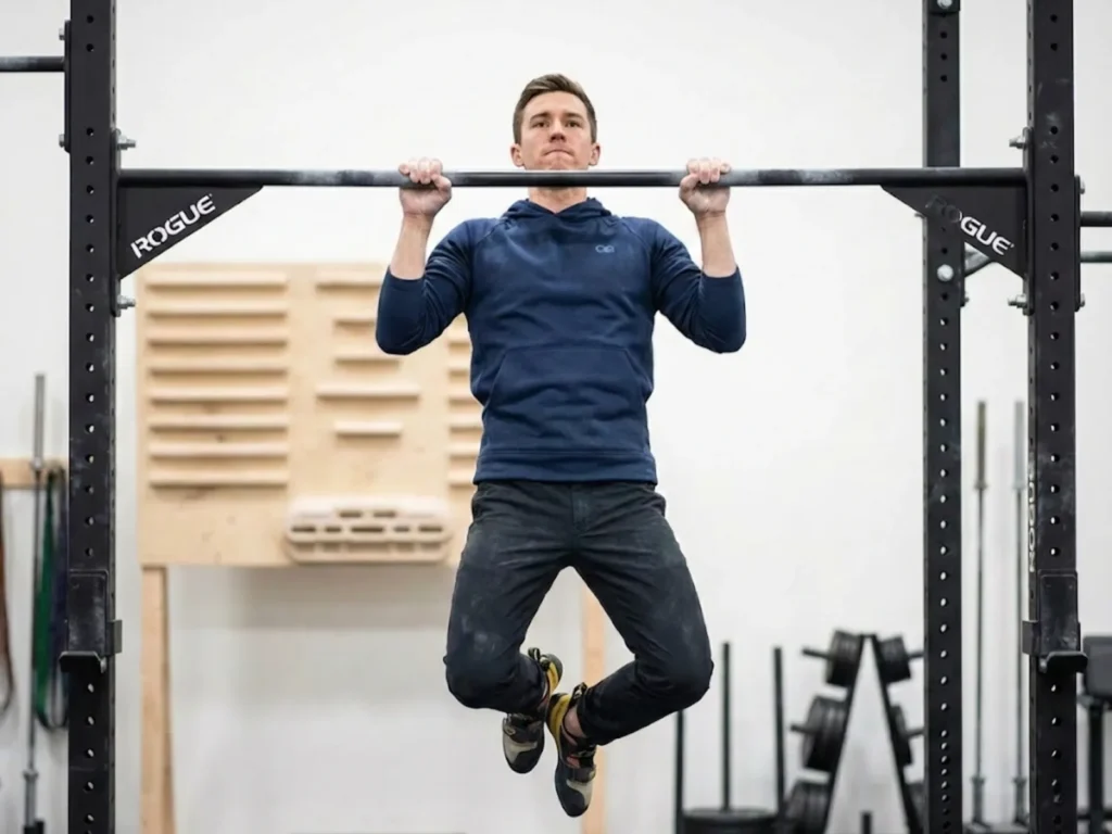 Climber performing pull-ups to demonstrate prerequisite strength for campus board training readiness