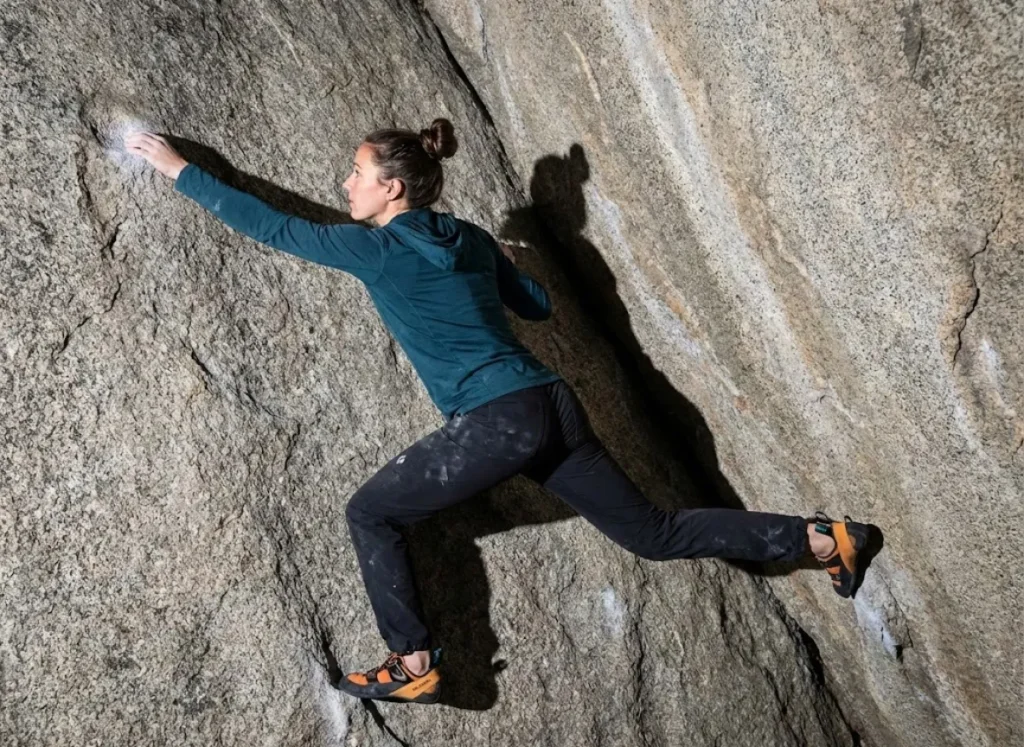 A professional climber executing a precise flagging move to counterbalance rotational force, demonstrating perfect body tension and vector alignment.
