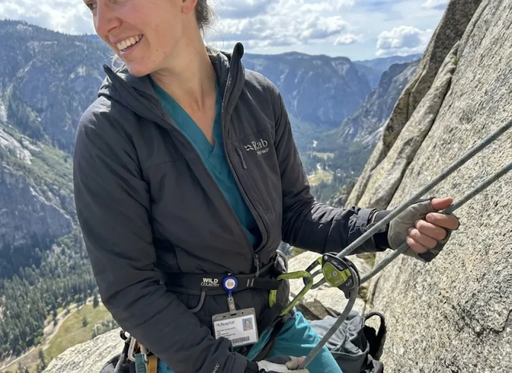 Healthcare worker climber belaying on granite ledge showing professional dual identity for sponsorship