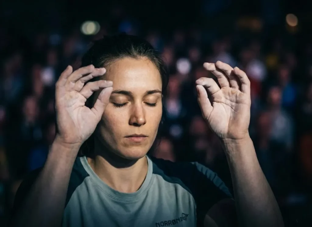 Close-up of a climber with eyes closed, using motor imagery to mime the hand movements of a route before climbing.