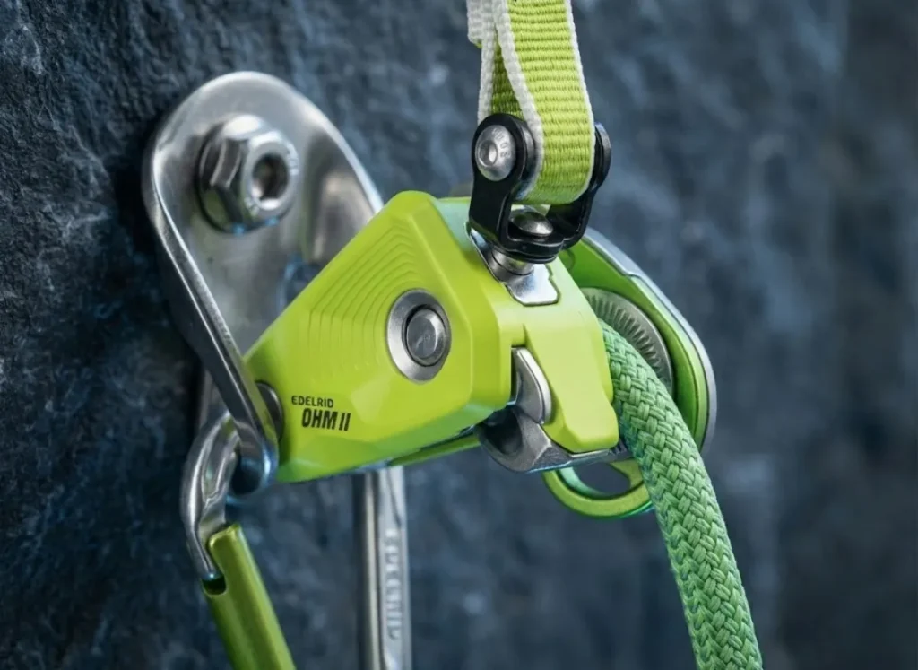 Extreme macro shot of the Edelrid Ohm device showing the steel braking mechanism and rope friction groove in high detail.
