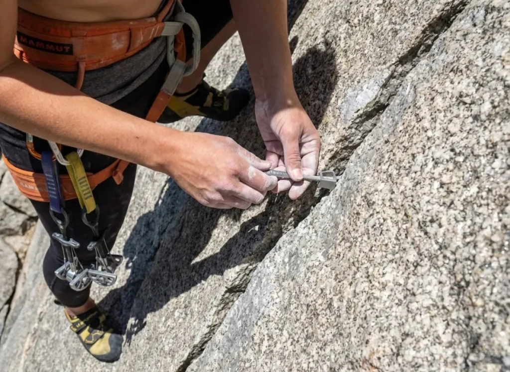 Climber placing DMM Wallnut into Yosemite granite crack showing crystal interlock for trad protection