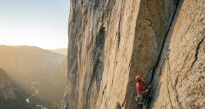Hiring a Guide for The Nose on El Capitan: Is $6,000 Worth It? Climber high on El Capitan's Nose route at golden hour with Yosemite Valley hazy far below