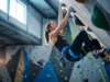 Pass Your Lead Climbing Test With These Habits A professional female climber calmly clipping a quickdraw on an overhanging indoor wall, wearing Arc'teryx gear, shot in a high-end gym with cinematic lighting.