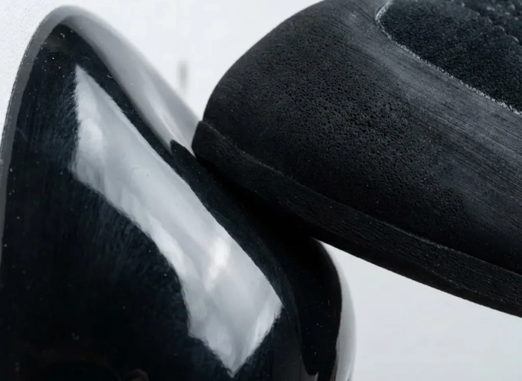 Macro close-up of Scarpa climbing shoe rubber compressing against a smooth, polished black dual-texture climbing hold surface.