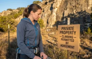 Climbing on Private Land? Liability Laws Every Climber Must Know Climber reviewing private land climbing access sign at crag entrance on Texas ranch property