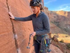 Rock Geology & Climbing Protection: The Field Manual Climber analyzing rock geology before placing trad protection in Indian Creek sandstone crack