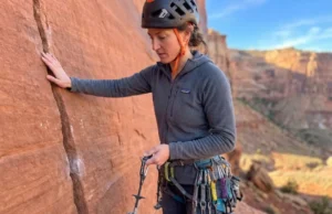 Rock Geology & Climbing Protection: The Field Manual Climber analyzing rock geology before placing trad protection in Indian Creek sandstone crack