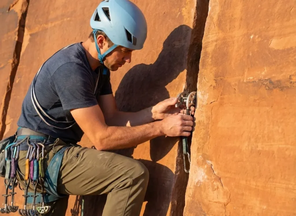 Climber placing Metolius Fat Cam in sandstone crack showing wide lobe distribution for soft rock protection
