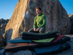 Stack Pads To Eliminate Gaps In Landing Zones A professional climber stands confidently on a meticulously stacked system of Organic Climbing and Black Diamond crash pads at the base of a highball boulder during sunset in the Buttermilks.