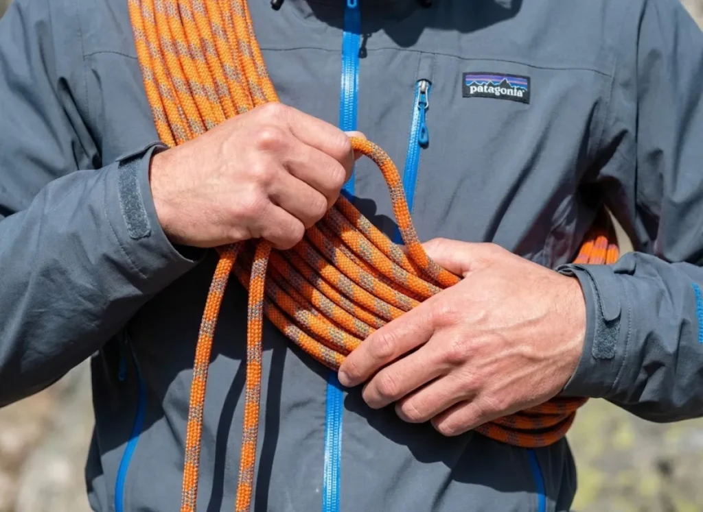 Detailed view of a climber managing a Kiwi Coil rope system across their chest, wearing a Patagonia jacket, highlighting efficient rope management techniques.
