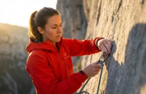 UIAA Safety Standards Explained: Know Your Gear Limits A professional climber on a limestone cliff face clipping a rope into a quickdraw, illuminated by golden hour sunlight, highlighting the texture of Arc'teryx gear and the focus in their eyes.