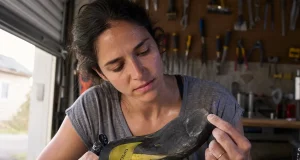 How to Resole Climbing Shoes So They Don’t Peel Worn climbing shoe held sole-up on a workbench before a resole, toe rubber thinned through