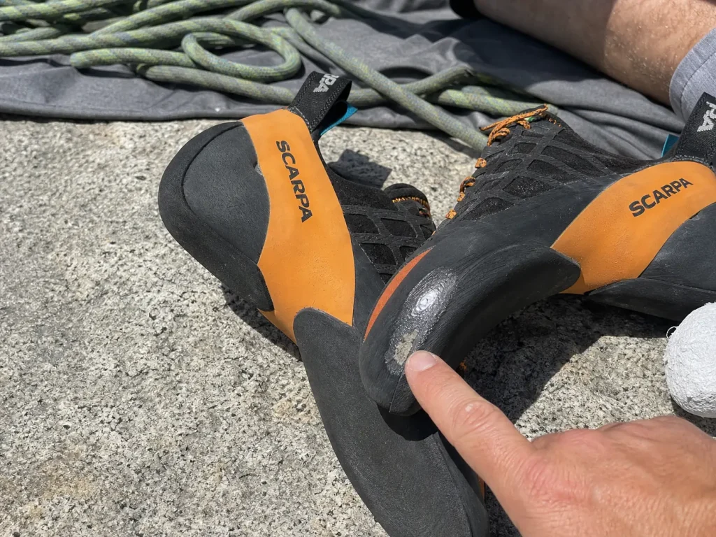 Two climbing shoes side by side showing sole wear stages, one with rand exposed at the toe