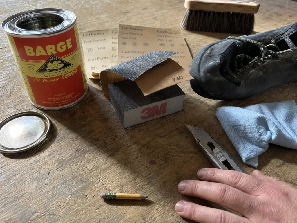 At-home climbing shoe resole kit laid out on a workbench with contact cement, sandpaper and a block