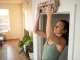 Best Hangboard for Small Spaces (A Renter’s Honest Review) Climber dead hanging on wooden hangboard mounted in apartment doorway for small space training