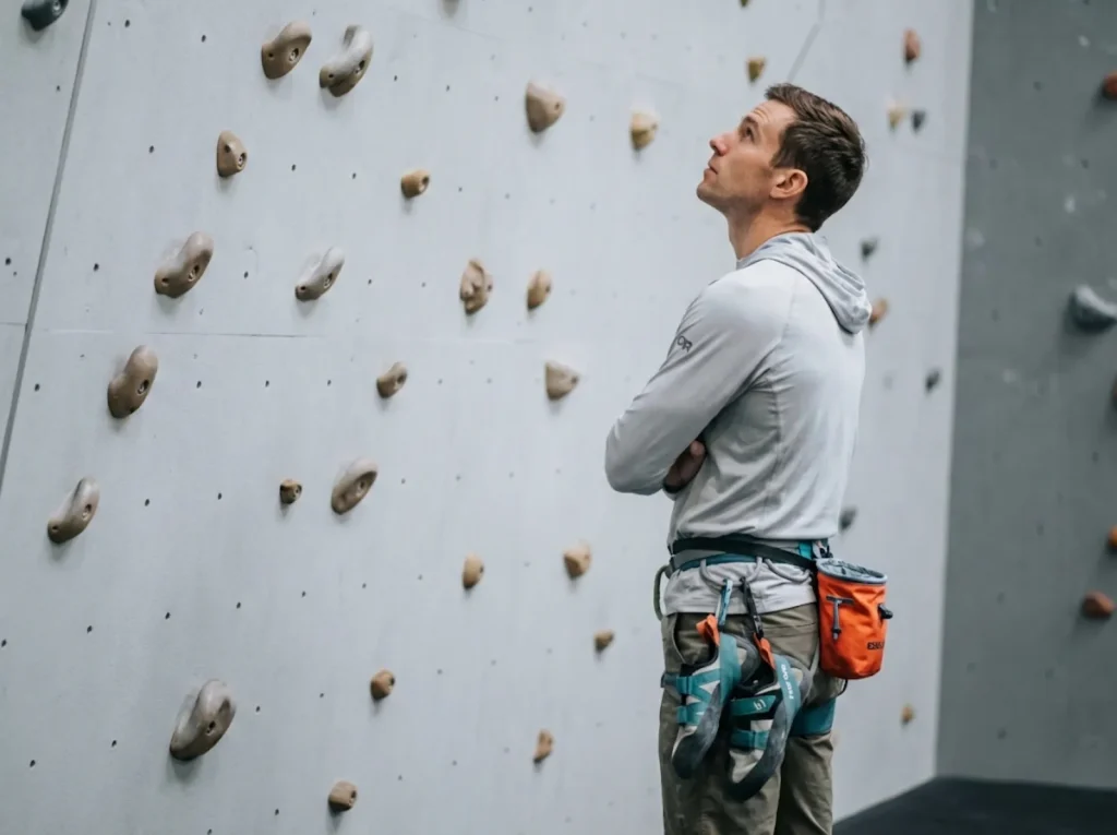 Climber studying boulder problem alone without unsolicited beta spray in gym