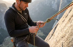 The Knot-Pass Mistake That Endangers Rappellers Climber rigging a Prusik backup above a joining knot mid-rappel on a granite wall