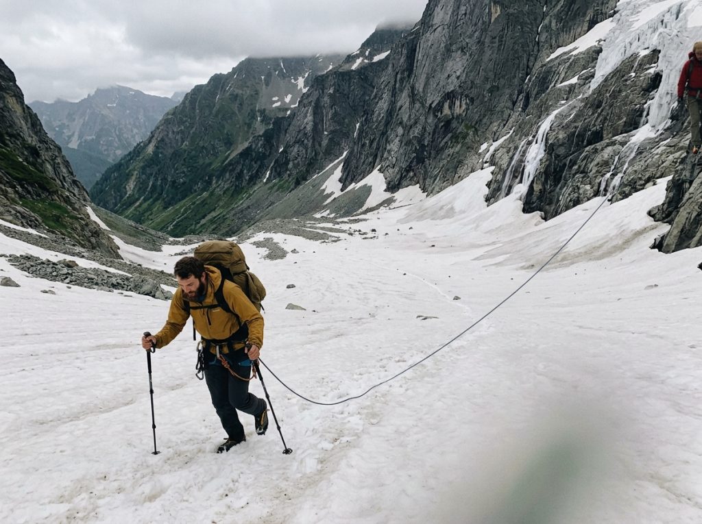 Two roped climbers crossing a remote glaciated basin far below jagged Cascade peaks