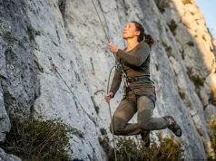 The Soft Catch Trick Most Belayers Get Wrong Belayer jumping to give a soft catch on a limestone sport route, Petzl GriGri, golden light