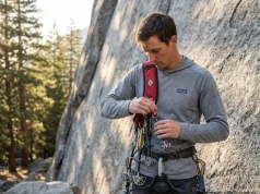 The Gear Sling Trick That Stopped My Trad Fumbles Trad climber racking cams onto a Black Diamond padded gear sling at Yosemite granite wall, golden hour light