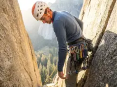 I Tested 3 Rack Systems for 6 Months on Real Routes Climber reaching for cam on organized harness rack during multi-pitch crack climb