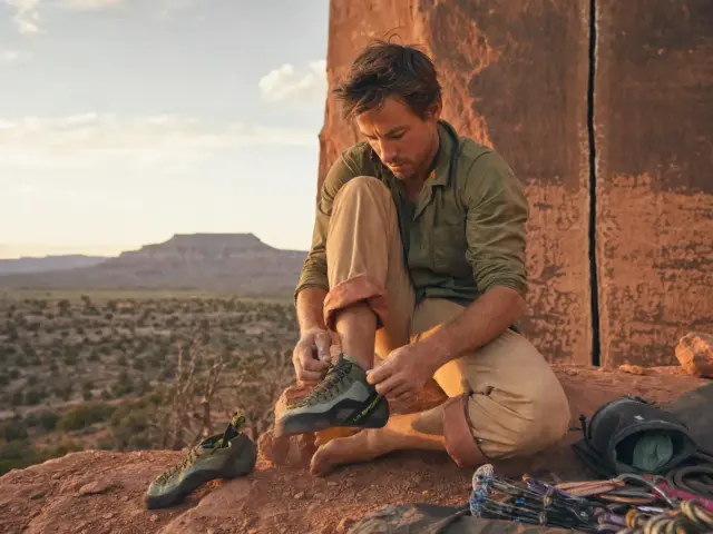 0-best-crack-climbing-shoes-tc-pro-indian-creek Climber lacing La Sportiva TC Pro crack climbing shoes below a red sandstone splitter at Indian Creek