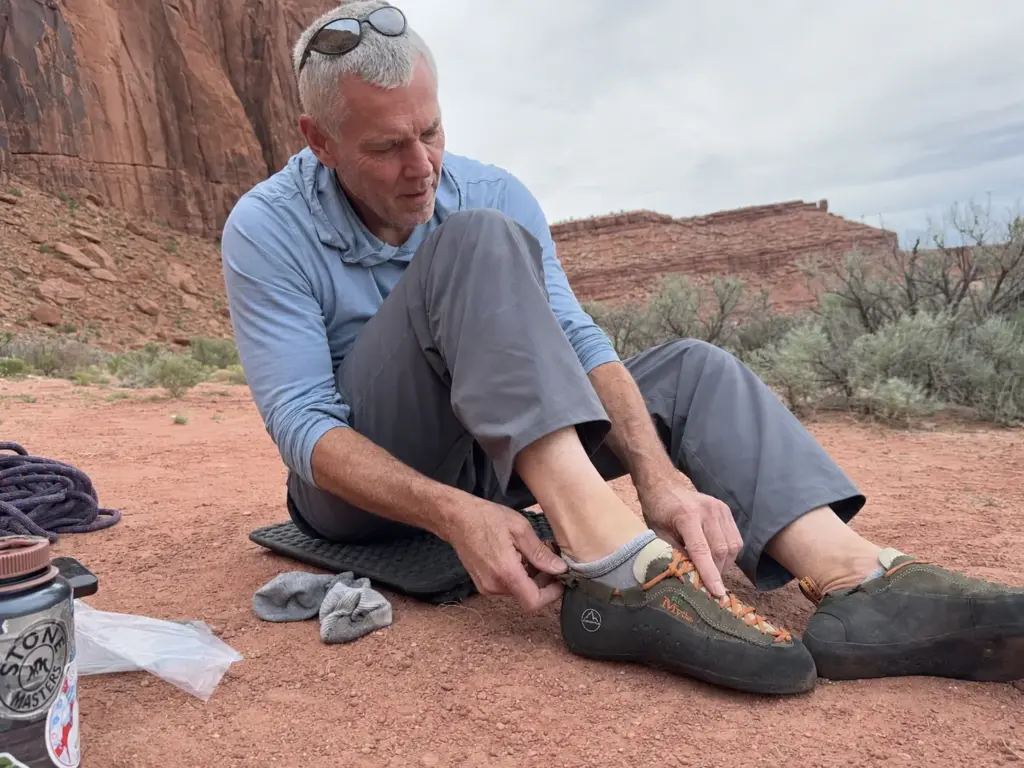 Climber checking the fit of La Sportiva Mythos crack climbing shoes at the base of a route