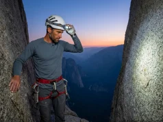 Best Headlamp for Climbing 2026 (One Surprised Me) Climber adjusting BioLite Range 400 headlamp on a Petzl helmet at a granite belay ledge at blue hour