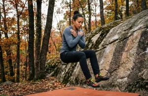 3 Bouldering Fall Mistakes That Send You to the ER Female boulderer mid-fall with T-Rex arms over crash pad at forest granite crag