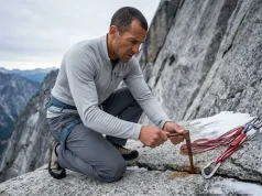 Climbing Anchor Failure Case Studies That Changed How I Rig Climber inspecting a rusted angle piton at a rappel station on a granite alpine crag, anchor failure analysis