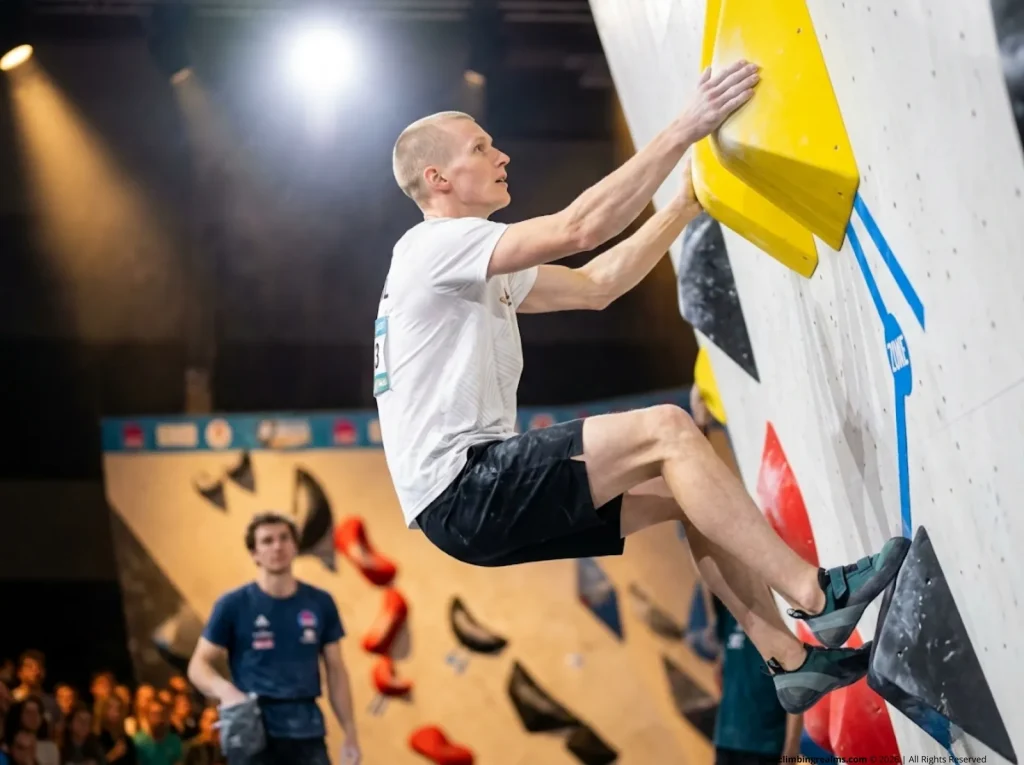 Male competition climber achieves and controls the Top hold with both hands matched at indoor bouldering final
