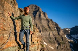 How to Climb Glacier National Park Without a Guide Climber on exposed argillite ridge in Glacier National Park, helmet and harness ready for technical ascent