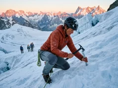 How to Build a Snow Anchor That Holds in Any Snow Mountaineer building a snow anchor on a steep glacier slope at dawn with ice axe and snow picket