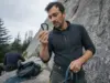 Why Your Carabiner’s Big kN Number Misleads You Climber reading the kN strength ratings stamped on a locking carabiner spine at the base of a route