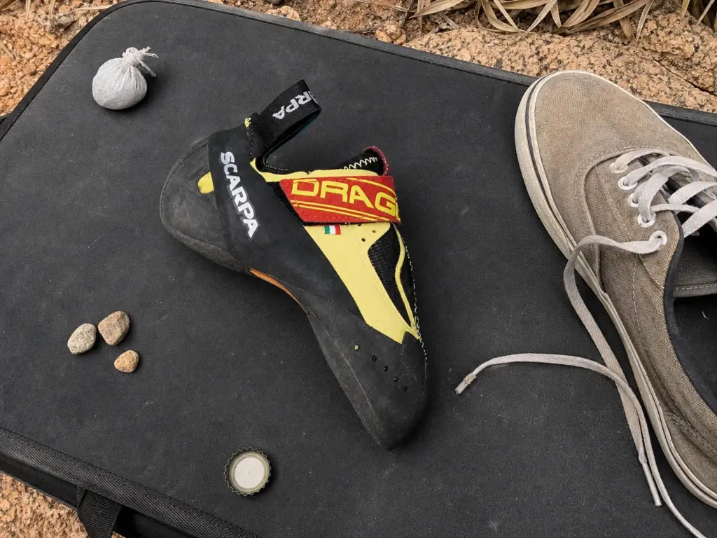 Downturned Scarpa Drago climbing shoe on a crash pad showing the aggressive banana curve
