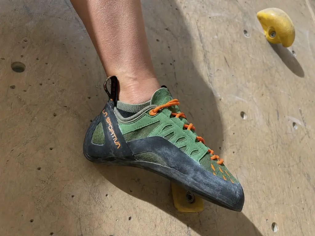 Close-up of a climbing shoe toe edging on a small foothold showing how a snug fit transmits force