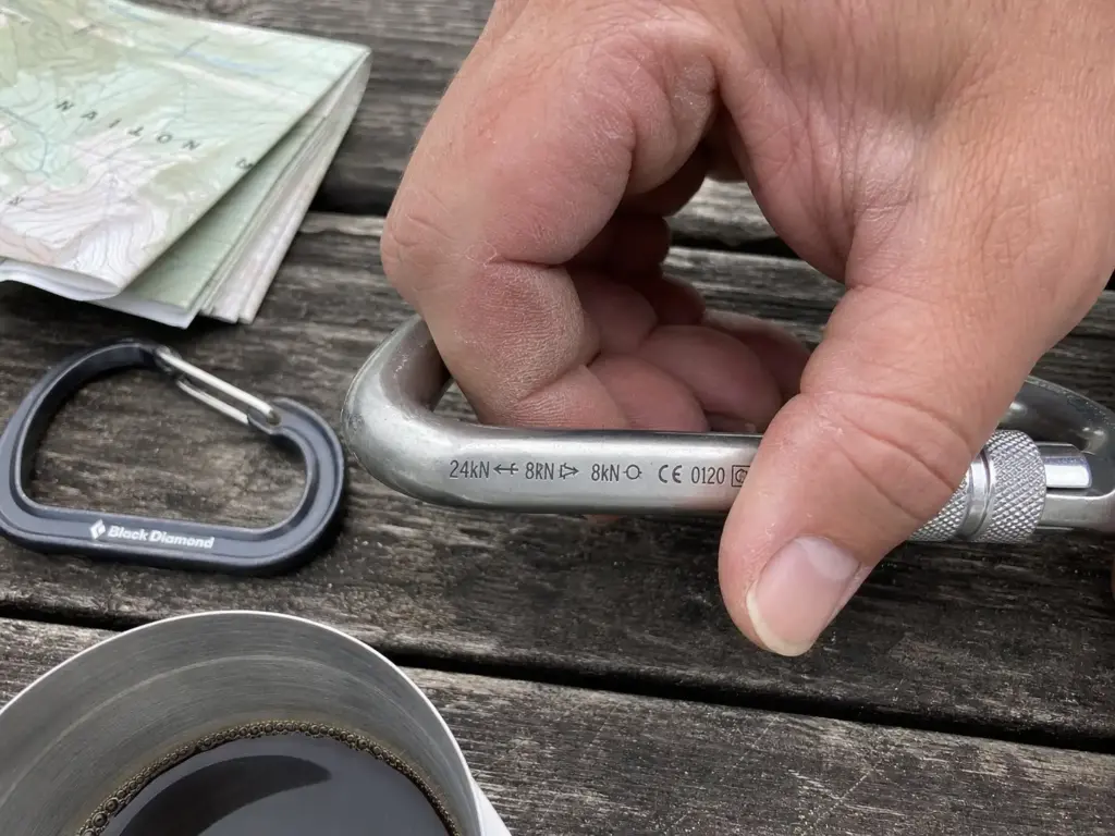 Close-up of kN force ratings etched on a climbing carabiner spine next to the UIAA and CE marks