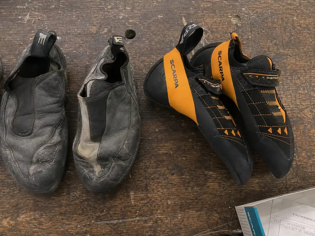 Leather and synthetic climbing shoes side by side on a gym bench showing different upper materials