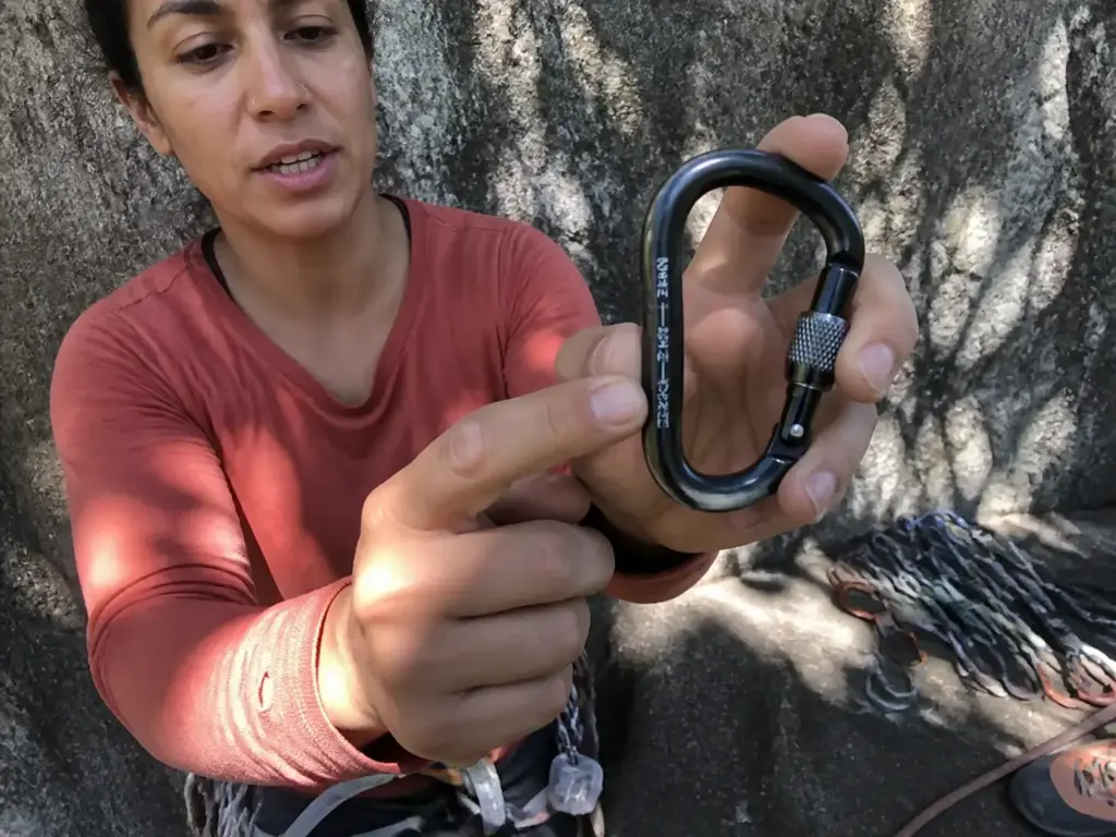Locking HMS carabiner held up showing the three axis strength rating pictograms on its spine
