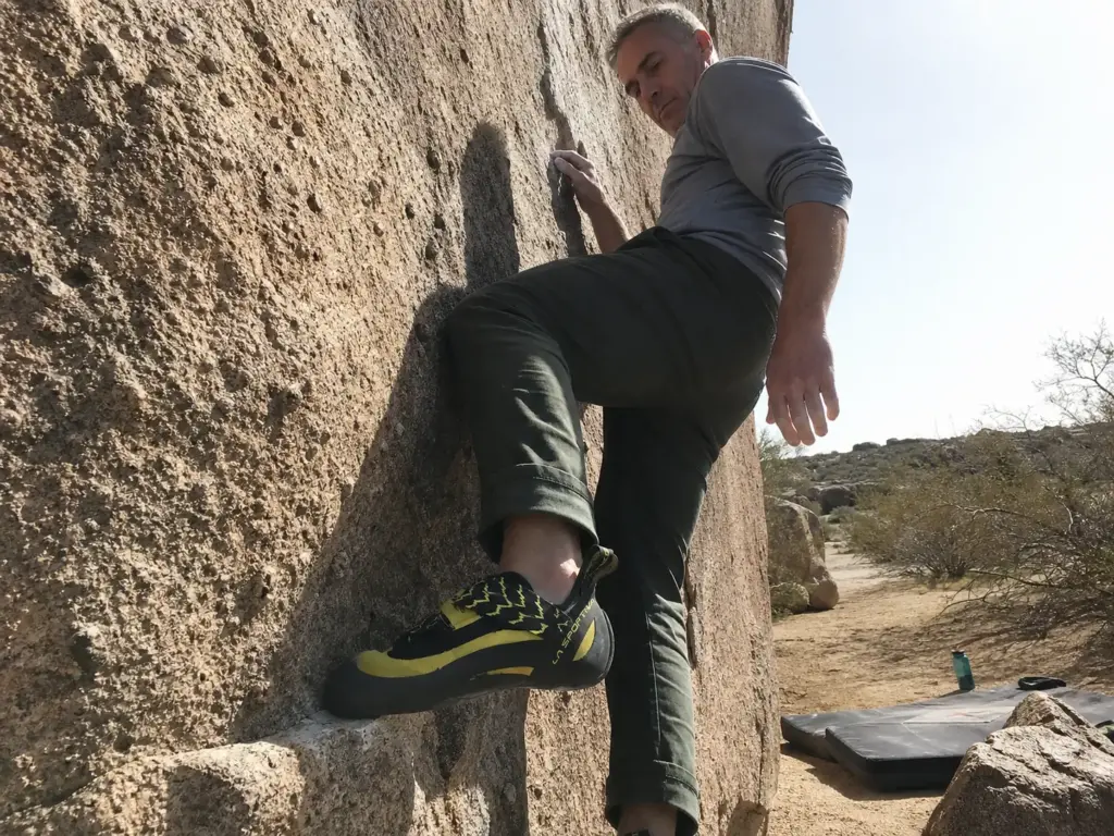 Climber standing on a small edge on vertical rock at Hueco Tanks in moderate climbing shoes