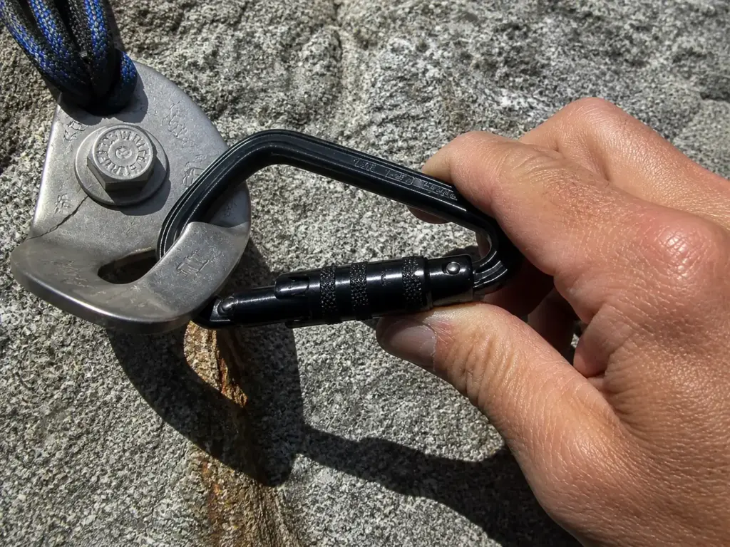 Carabiner sitting crooked against a wide bolt hanger showing how cross-loading happens on the minor axis