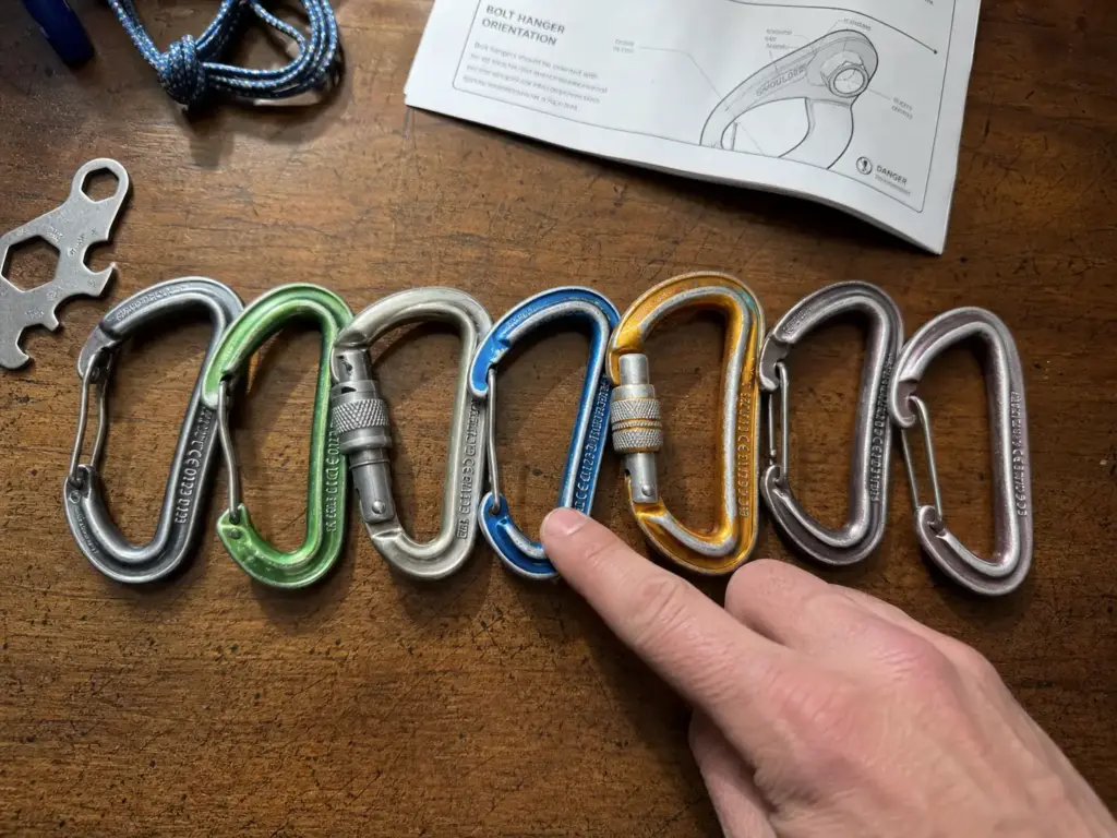 Assorted climbing carabiners laid out showing UIAA and CE certification marks stamped on each spine